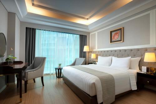 a hotel room with a bed and a desk and a window at Wyndham Panbil Batam in Batam Center