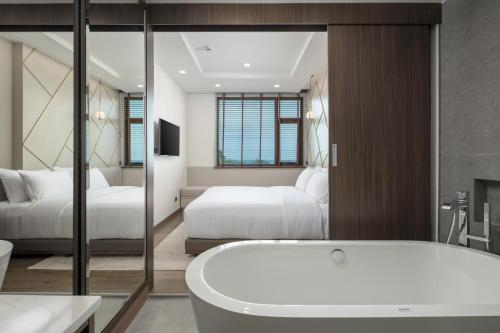 a bathroom with two beds and a bath tub at The Proud Karon Beach Phuket Trademark Collection By Wyndham in Karon Beach