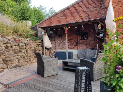 a patio with chairs and an umbrella and a brick building at Gemütliches Fachwerkhaus Hessen Thüringen in Herleshausen