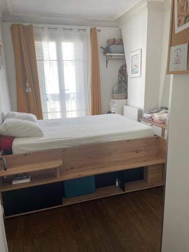 - une chambre avec un grand lit et un cadre en bois dans l'établissement Appartement proche Paris, à Saint-Ouen-sur-seine, à Saint-Ouen