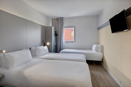 a hotel room with two beds and a tv at B&B HOTEL Girona 2 in Salt