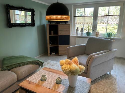 a living room with a couch and a table with flowers at Ferienhaus Juule in ruhiger Lage, Terrasse, WLAN in Krummin