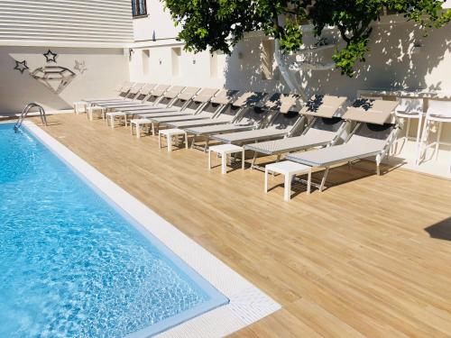 a swimming pool with white chairs and a swimming pool at Hotel Smeraldo in Qualiano