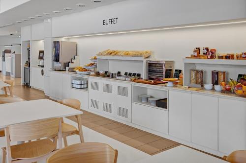a kitchen with white cabinets and a table and chairs at B&B HOTEL Girona 3 in Salt