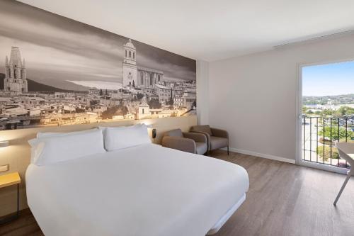 a hotel room with a white bed and a large window at B&B HOTEL Girona 3 in Salt