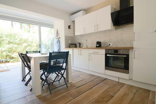 une cuisine avec des armoires blanches et une table et des chaises dans l'établissement T2 jardin, 100m de la plage, à Sanary-sur-Mer