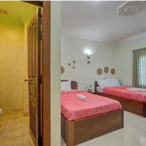 a bedroom with two beds with red sheets at DV Villa in Siem Reap