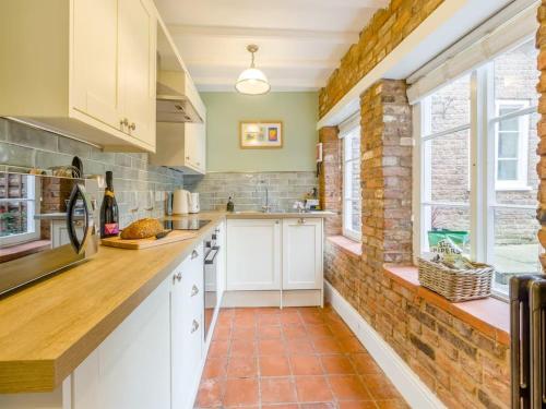 a kitchen with white cabinets and a brick wall at Papist Hall Cottages in Barrow upon Humber