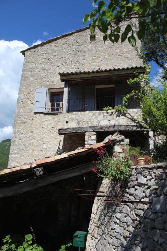 - un bâtiment en pierre avec une fenêtre et un balcon dans l'établissement Le Mardaris, à Reilhanette
