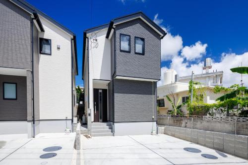 a house with a black and white facade at オープンセール 2棟貸切 最大20名ビーチまで車で4分 駐車場4台 tla&tdy ツインズロッジA棟B棟貸切 in Yomitan