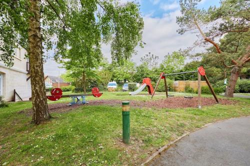un parc avec une balançoire installée dans la pelouse dans l'établissement Appartement 2 pièces, Rez de jardin et terrasse, à Deauville