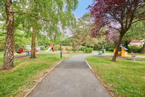un chemin dans un parc avec une aire de jeux dans l'établissement Appartement 2 pièces, Rez de jardin et terrasse, à Deauville