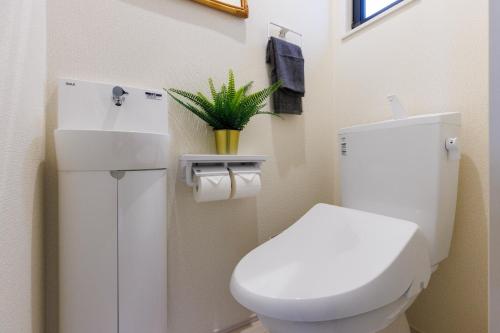 a bathroom with a toilet and a plant in it at オープンセール 2棟貸切 最大20名ビーチまで車で4分 駐車場4台 tla&tdy ツインズロッジA棟B棟貸切 in Yomitan