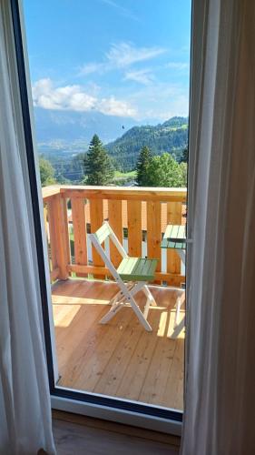 a sliding glass door with a chair on a deck at Ferienwohnung Maria & Luis in Kolsass