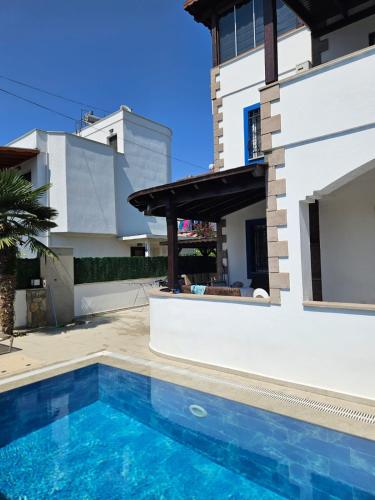 a villa with a swimming pool in front of a house at Villa à Turgutreis in Bodrum City
