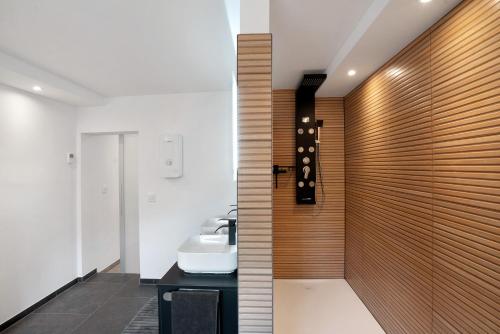 ein Badezimmer mit einem Waschbecken und einer Holzwand in der Unterkunft Appartment Antilope im Würmtal in Gräfelfing