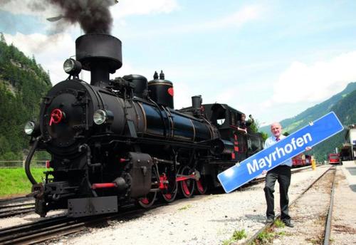 a man is standing next to a train at Hotel Schwarzer Adler in Hippach