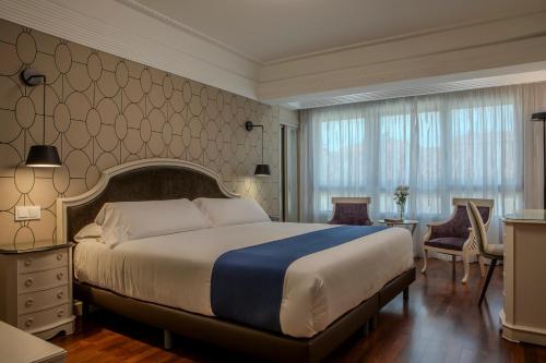 ein Hotelzimmer mit einem großen Bett und einem Schreibtisch in der Unterkunft Hotel Corona de Castilla Burgos in Burgos