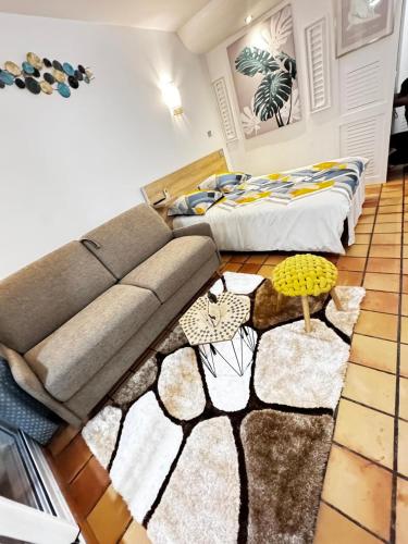 a living room with a couch and two beds at Studio MESANGE TARTANE in La Trinité