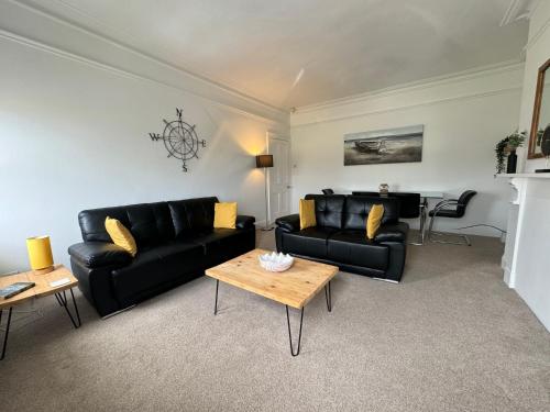 a living room with black leather furniture and a table at Longsands Beach, Apartment 4, Tynemouth in Tynemouth
