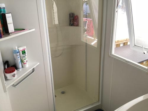 une douche avec une porte vitrée dans une salle de bain dans l'établissement Mobile home 3 chambres Camping Flower Odalys, à Longeville-sur-Mer