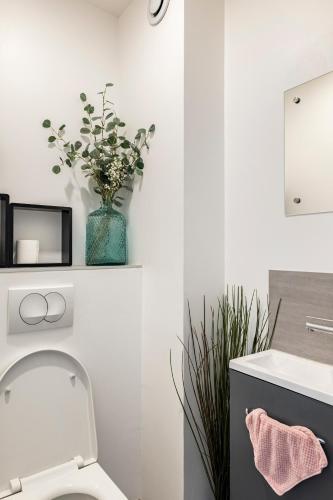 une salle de bain avec toilettes et un vase avec des fleurs dans l'établissement Part-Dieu (garage inclus) / Brotteaux, à Lyon