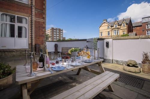 a wooden table on a patio with wine bottles and glasses at Bentinck Residence by Sasco Apartments in Lytham St Annes