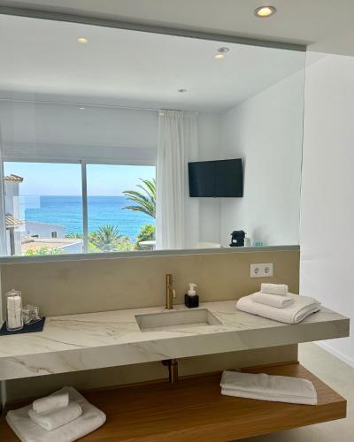 a bathroom with a sink with a view of the ocean at Tierratlanta Suites in Zahara de los Atunes
