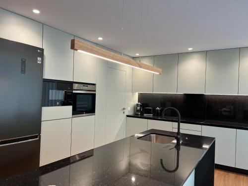 a kitchen with white cabinets and a black counter top at Casa da Arda, piscina exclusiva, entre mar e a montanha in Armada