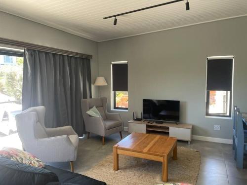 a living room with a tv and two chairs and a table at Cola Beach Nomads Nook in Sedgefield