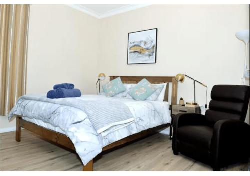 ein Schlafzimmer mit einem Bett und einem schwarzen Stuhl in der Unterkunft Cozy Mountain Cottage in Katoomba