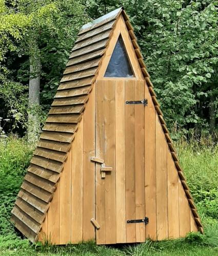 a wooden doghouse with a roof in the grass at Sepa Jõe Holiday Home in Riksu