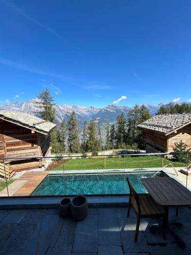 a pool with a table and a view of the mountains at MAD Retreat Hotel in Nendaz