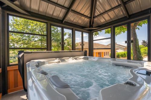 une baignoire jacuzzi dans une maison avec fenêtres dans l'établissement Gite des ifs piscine, jacuzzi dans le Beaujolais, à Le Bois-dʼOingt