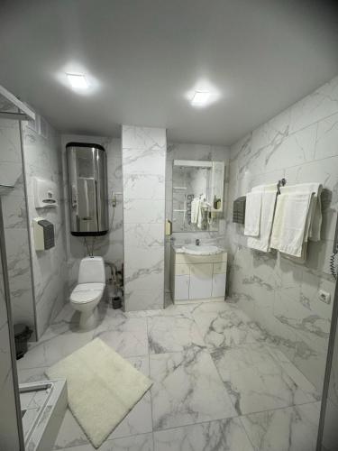 a white bathroom with a toilet and a sink at In hotel in Kamianets-Podilskyi