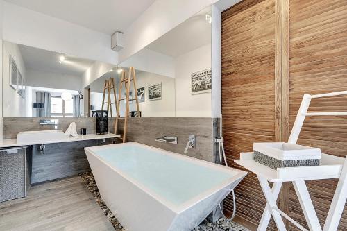 a bathroom with a tub and a sink and a mirror at Apartamenty Apartinfo Aura in Gdańsk