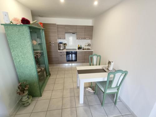 une cuisine avec une table blanche et des chaises vertes dans l'établissement Bas de maison calme proche mer et Venise Provençale, à Martigues