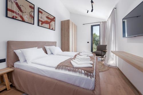 a bedroom with a bed with white sheets and a television at Villa Albona in Poreč