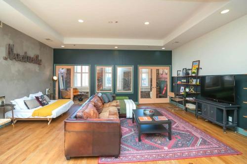a living room with a couch and a flat screen tv at Broadway Penthouse Above Live Music & Bars in Nashville