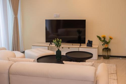 a living room with white furniture and a large screen tv at GTC Residence, Luxurious Living in The Heart of Nairobi, Westlands in Nairobi