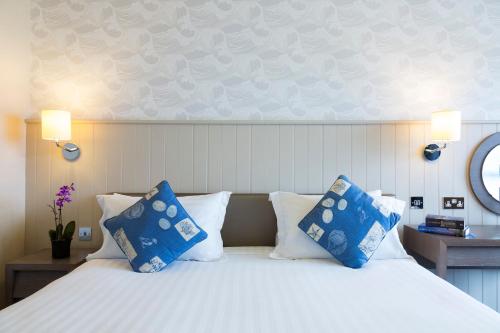 a bedroom with a bed with blue and white pillows at Golden Sands in St Brelade