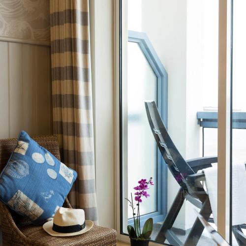 a hat sitting on a chair next to a window at Golden Sands in St Brelade