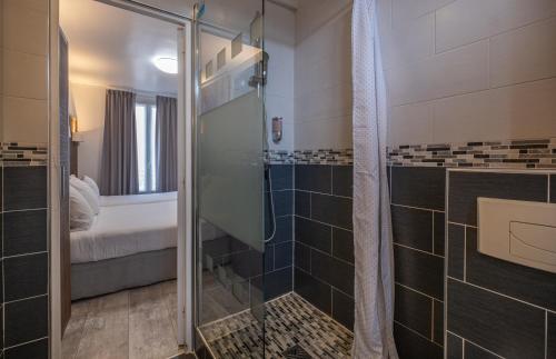 a bathroom with a walk in shower and a glass shower stall at Hotel Luxor in Issy-les-Moulineaux