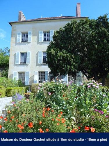 a white house with a lot of flowers in front of it at Amman Studio avec terrasse au cœur du village impressionniste in Auvers-sur-Oise