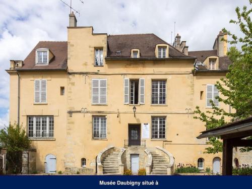 a large yellow building with stairs in front of it at Amman Studio avec terrasse au cœur du village impressionniste in Auvers-sur-Oise