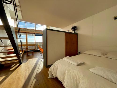 une chambre avec un lit blanc et une grande fenêtre dans l'établissement Duplex Le Corbusier, à Marseille