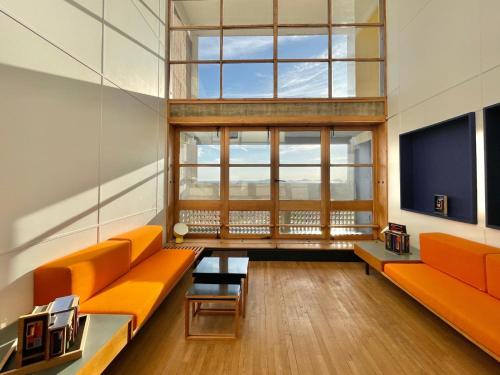 Cette grande chambre dispose d'un mobilier orange et d'une grande fenêtre. dans l'établissement Duplex Le Corbusier, à Marseille