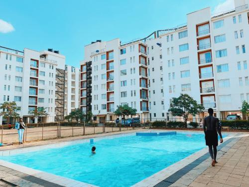 a man standing in front of a swimming pool with buildings at Racecourse gardens furnished apartments in Nairobi