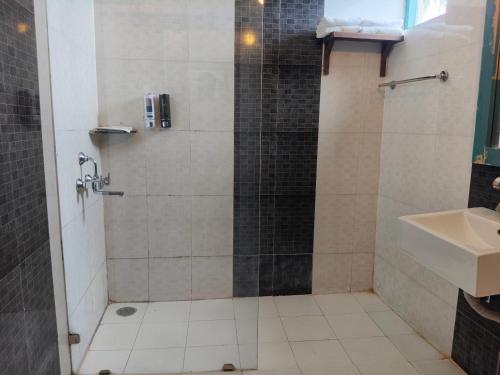 a shower with a glass door next to a sink at Aacorn Hideaway Resort & Spa in Rāmnagar