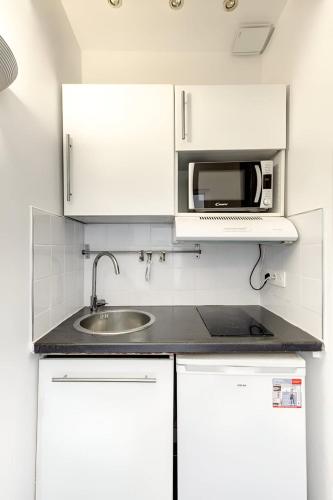 une cuisine blanche avec un évier et un micro-ondes dans l'établissement Bluestay 187 - Charmant studio à Paris, à La Celle-sous-Gouzon